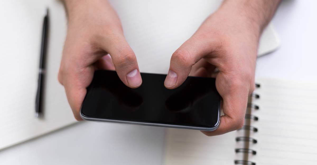 Tangan memegang HP dengan hati-hati, casing dan tempered glass tetap disarankan untuk pemakaian harian