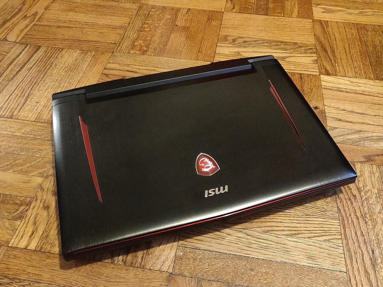 Laptop gaming di atas lantai kayu, ilustrasi beban game berat di laptop